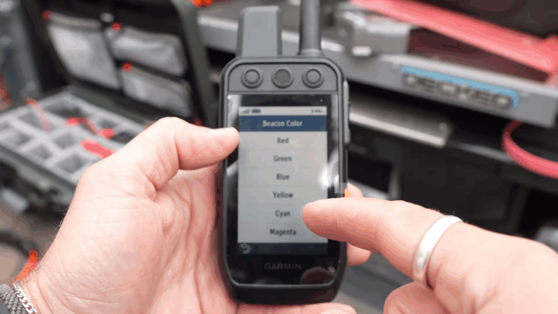 A person uses a Garmin handheld tracker to select beacon colors for improved visibility and safer dog tracking in the field